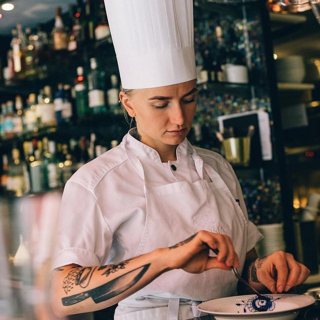 Kvinna i kockkläder förbereder en tallrik i en restaurang.