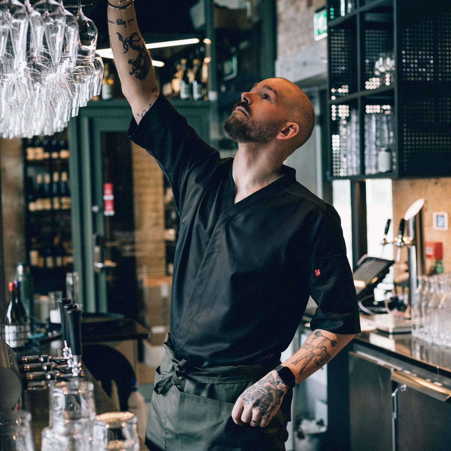 Man i arbetskläder från Segers sträcker sig efter ett glas från baren.