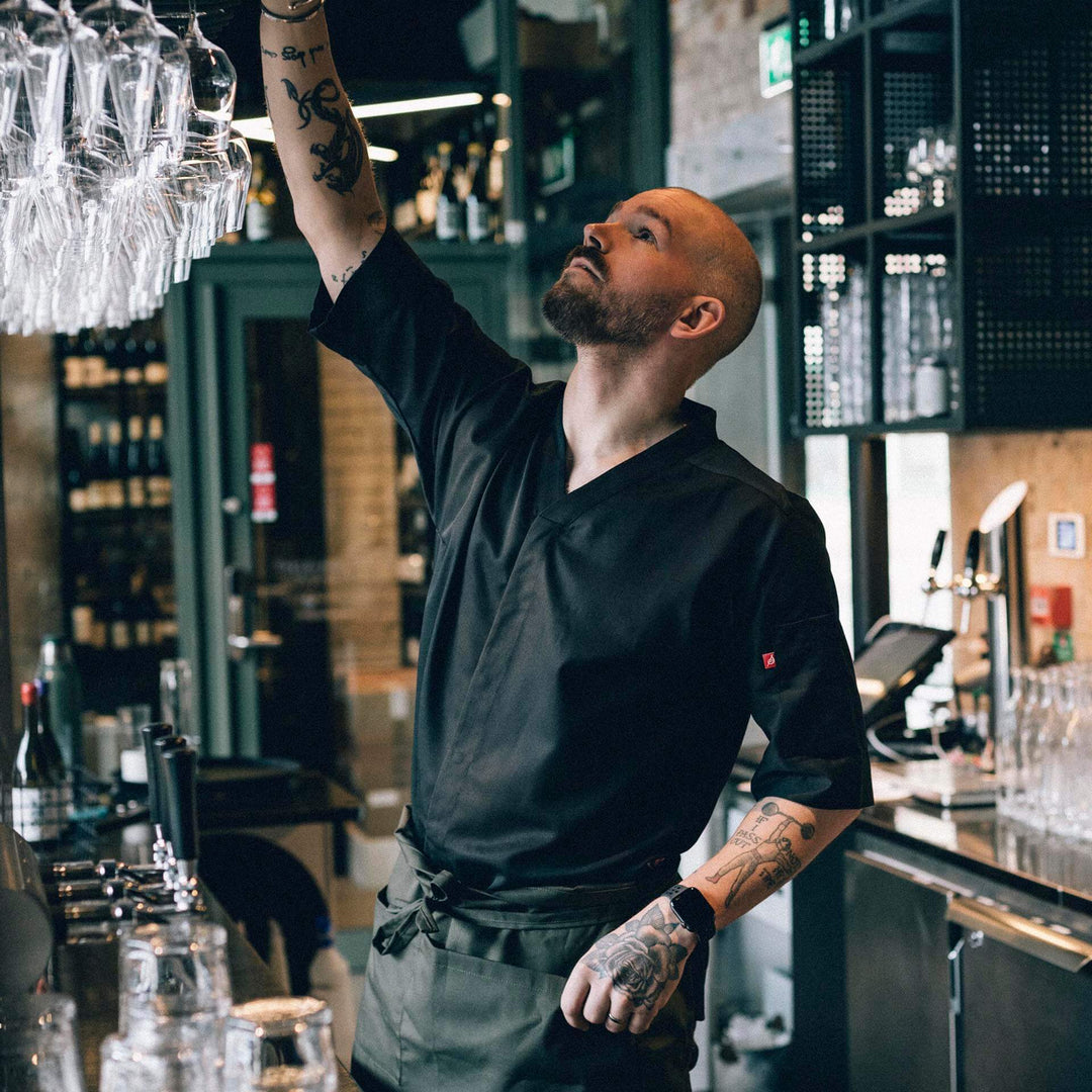 Man i arbetskläder från Segers sträcker sig efter ett glas från baren.
